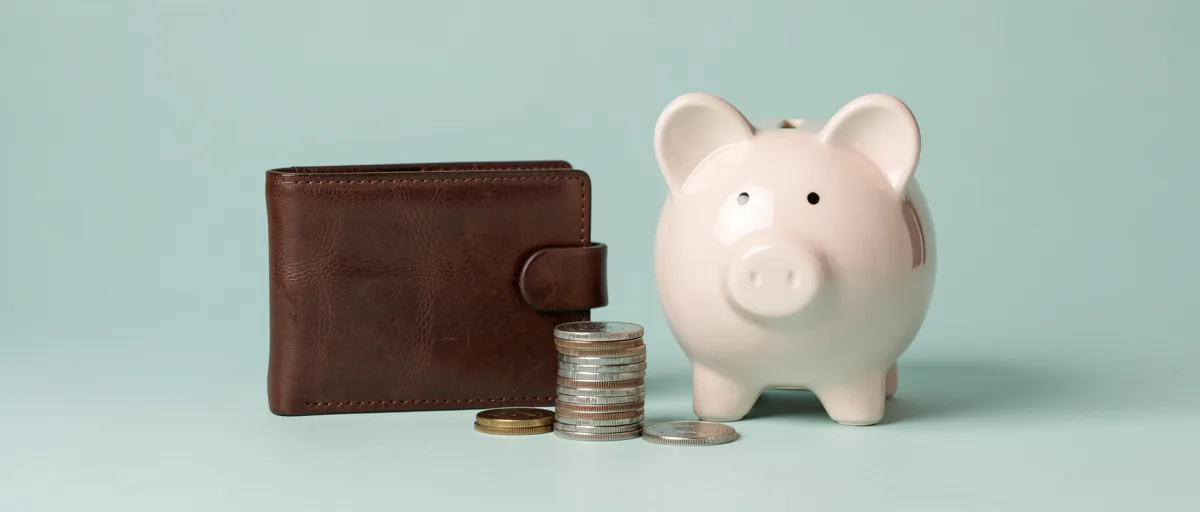 A leather wallet beside a stack of coins and a ceramic piggy bank — illustration for Best Revolut Alternatives in Europe for 2026
